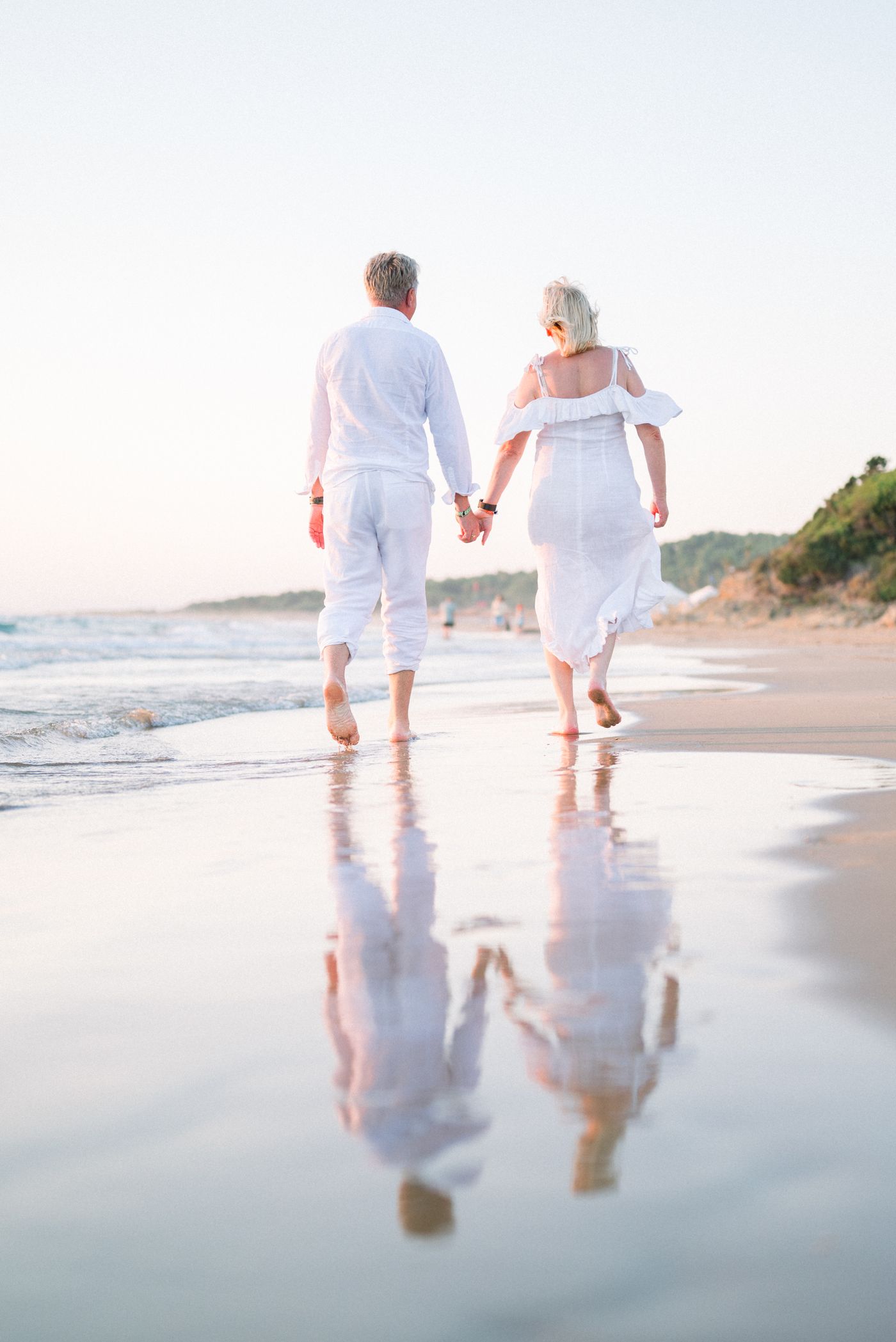 A couple walking barefoot along the shoreline